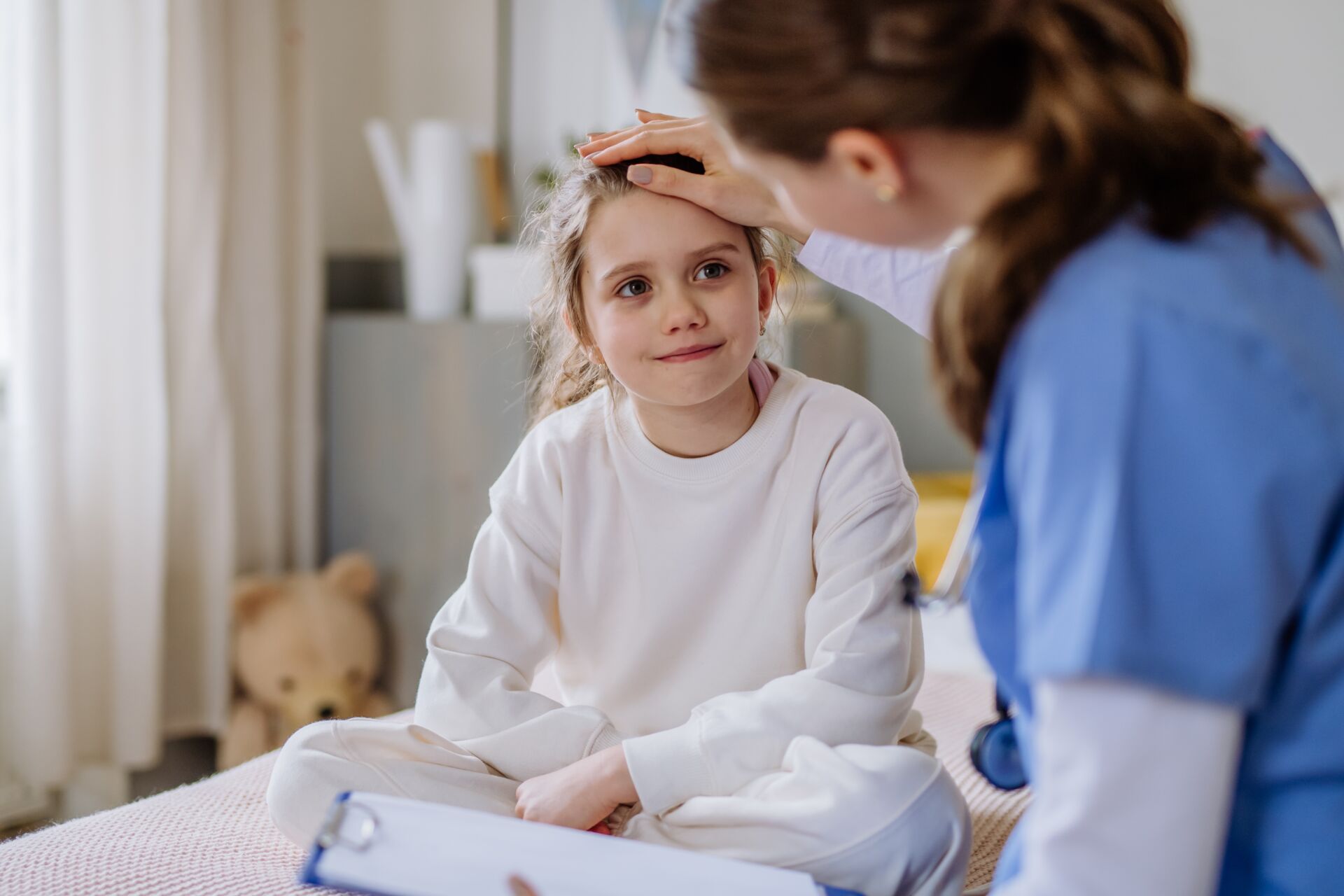 Eine Krankenschwester misst bei einem Kind Fieber in einem Kinderzimmer
